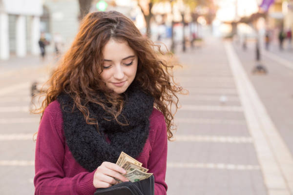 young shopper woman taking out money from wallet on street